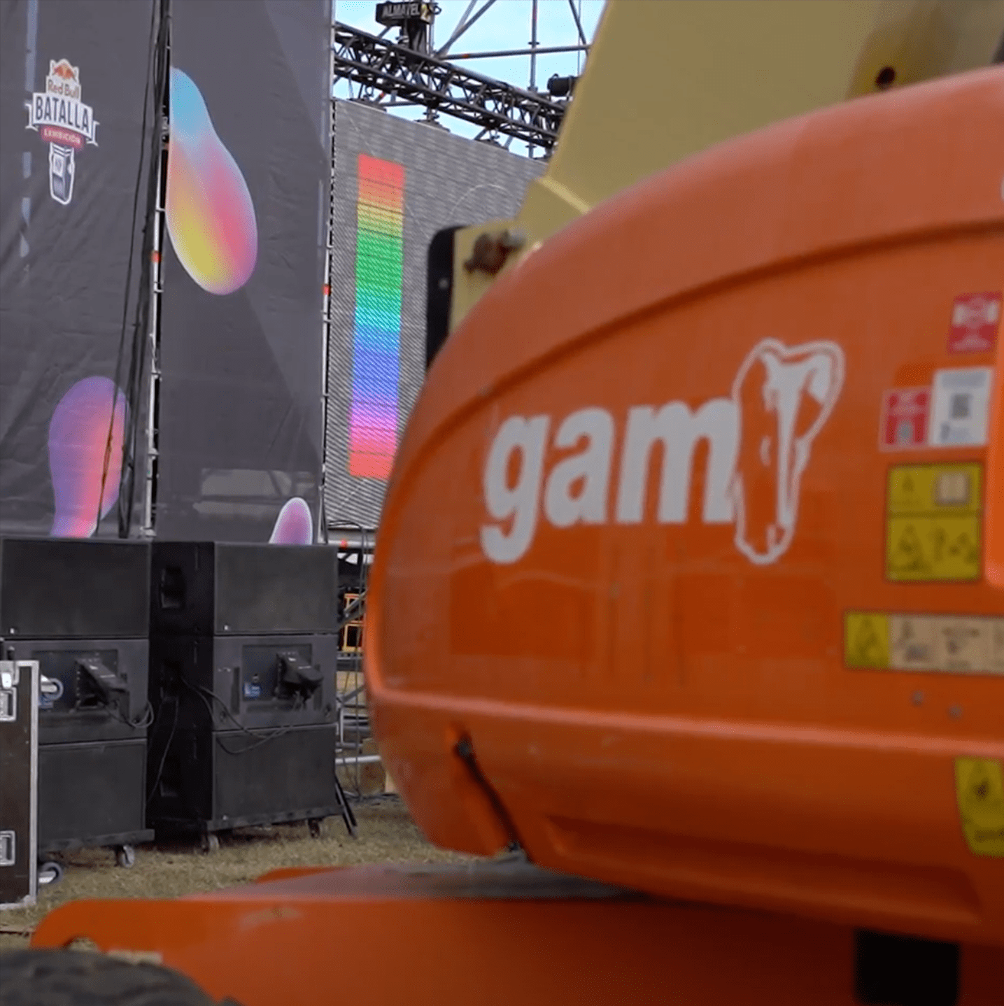 Parte trasera de un escenario con el logo de GAM en una grúa en primer plano